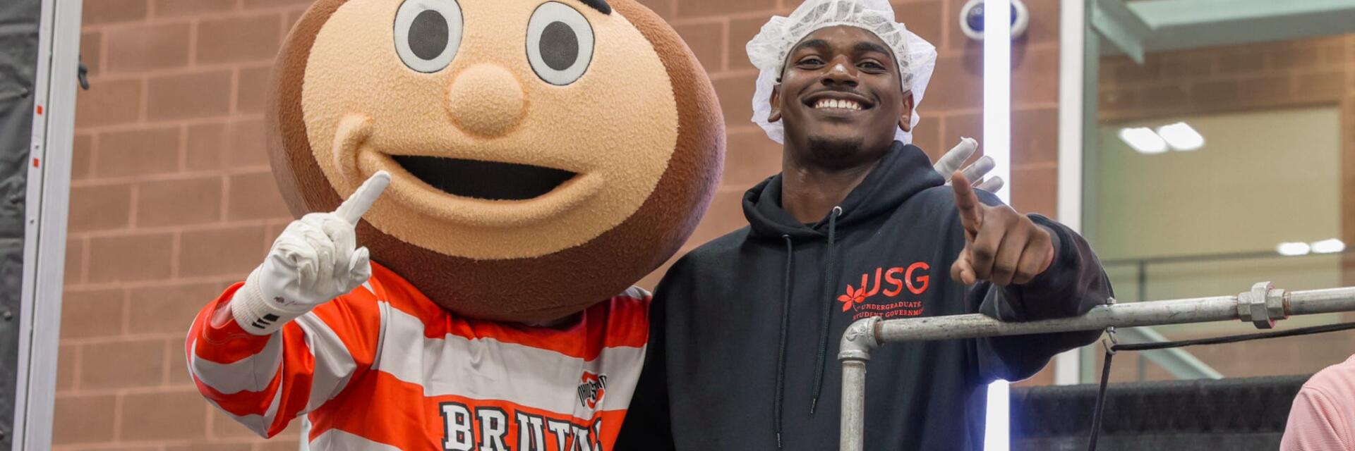 Brutus, Ohio State's mascot, and former president Justin Robinson smiling towards the camera