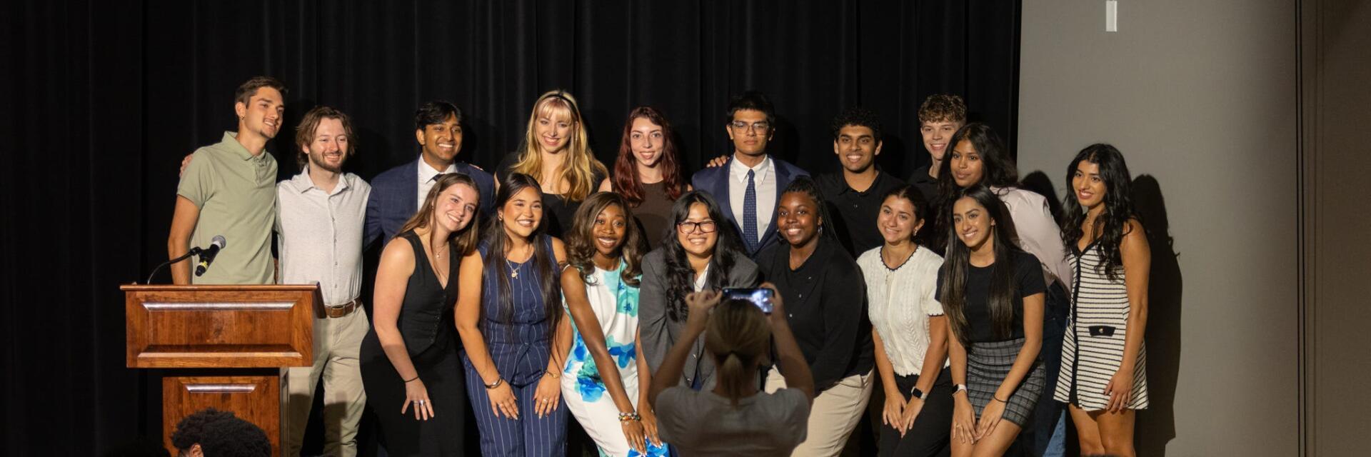 Group of students against a black backdrop, smiling